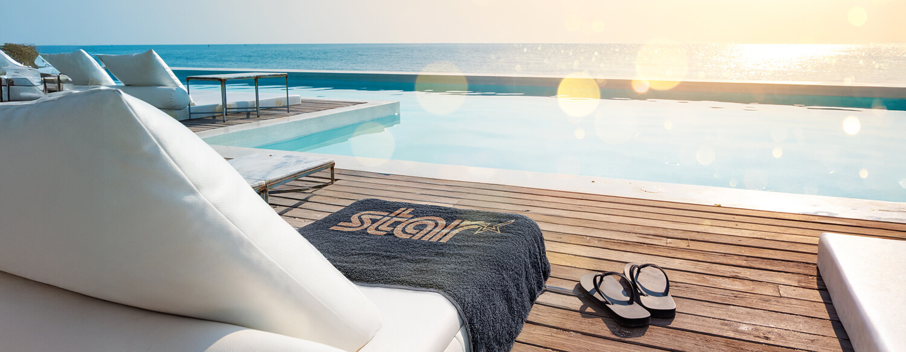 star towel on a lounger in front of a pool with a view of the sea